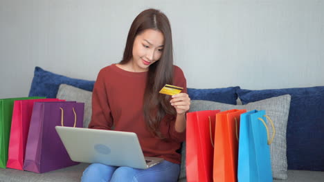 Mujer-Asiática-Sonriente-Comprando-En-Línea-Con-Tarjeta-De-Crédito-Y-Portátil