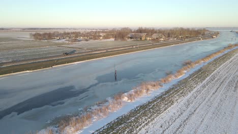 Person-ice-skating-on-natural-frozen-river-in-flat-land-of-Holland,-winter