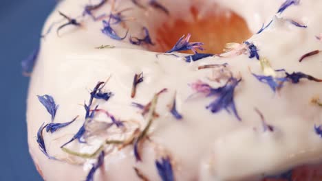 Donut-with-white-icing-and-edible-blue-flower-sprinkle-close-up