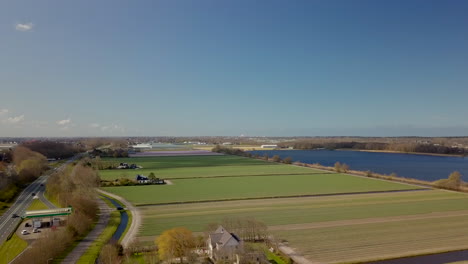 Vista-Aérea-De-Drones-De-Los-Hermosos-Campos-De-Cultivo-Cerca-Del-Lago-En-Noordwijk,-Países-Bajos