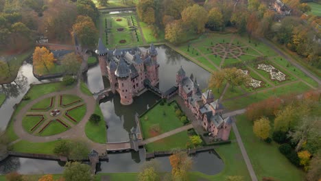 Aerial-at-magical-medieval-castle-De-Haar-with-public-gardens-at-dawn