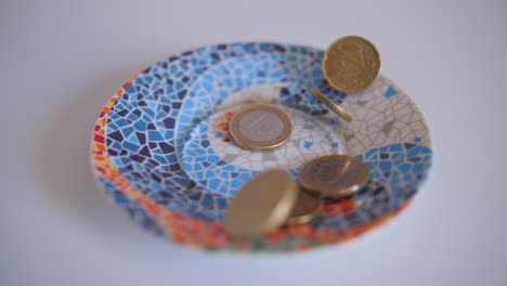 Euro-coins-falling-in-a-glass-vessel-on-a-table-