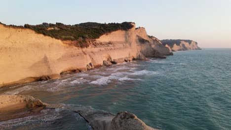 Playa-De-Acantilados-Con-Olas-A-La-Hora-Dorada,-Cabo-Drastis,-Corfú,-Grecia