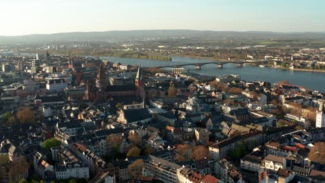 Drone-aerial-circle-around-the-Cathedral-church-of-Mainz-on-a-warm-spring-day-with-the-blue-Rhine-river-in-the-back