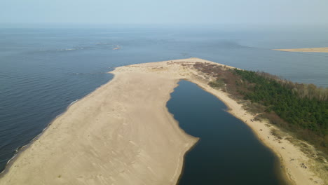 Aerial-side-shot-of-Mikoszewskie-lake-and-Vistula-River-ended-in-sandbank-of-Mewia-Lacha-Nature-Reserve-during-a-sunny-day,-Baltic-Sea-Poland