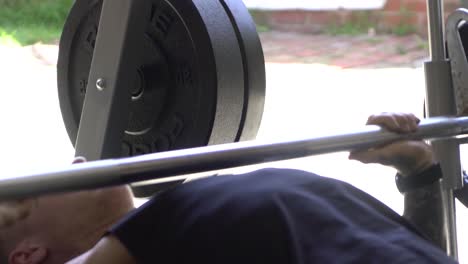 Muscly-man-in-home-gym-exercising-smith-machine-bench-press-close-up
