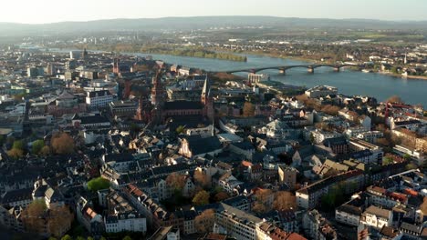 right-to-left-drone-move-showing-the-Cathedral-of-Mainz-in-the-middle-of-tiny-houses-on-a-warm-spring-day-with-the-Rhine-river-in-the-back