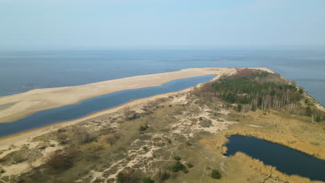 Drone-Vuela-Sobre-El-Lago-Mikoszewskie-Y-El-Río-Vistula-De-La-Reserva-Natural-Mewia-Lacha-Durante-Un-Día-Soleado,-Mar-Báltico-En-Segundo-Plano