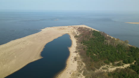 Drone-flying-sidewards-showing-beautiful-sandy-banks-of-Vistula-River-entering-in-Baltic-sea,-Poland-daytime-sunny-weather-at-Mewia-Lacha-Nature-Reserve
