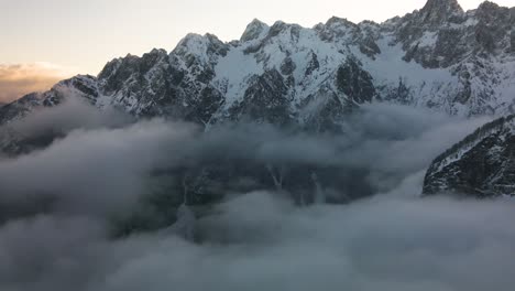 Antena-Sobre-Nubes-Rodantes-Contra-Picos-De-Montañas-Blancas,-Paso-Vrsic,-Eslovenia