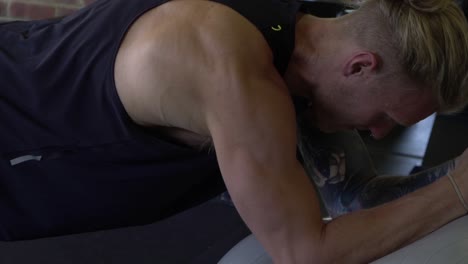 Muskulöser-Mann-Im-Heimfitnessstudio,-Der-Planken-Auf-Medizinball-Trainiert
