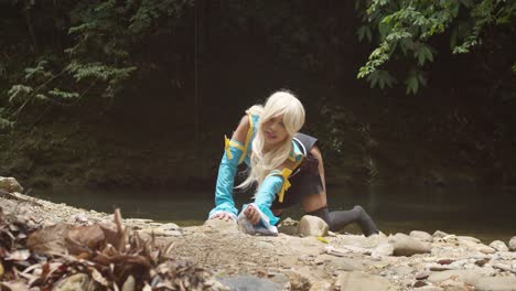 Sexy-Lucy-cosplayer-on-her-knees-picking-up-her-keys-from-the-ground-with-a-river-flowing-in-the-background