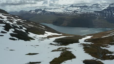 Melting-snow-on-mountain-slope-in-Iceland-with-view-of-Reyðarfjörður-fjord