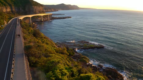 Magnificent-Sunrise-Overlooking-Modern-Highway-At-The-Edge-of-An-Island-In-Australia---aerial-shot