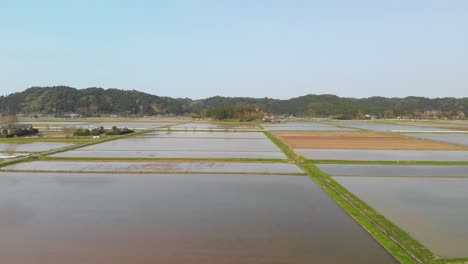 Beautiful-sideways-flight-over-water-filled-rice-fields-in-Japanese-countryside