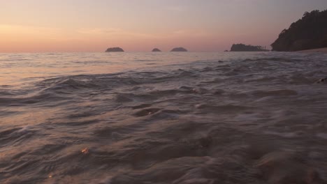 Strand-Mit-Sand-Und-Kleinen-Felsen-Mit-Inseln-Und-Landzunge-In-Der-Ferne-Bei-Sonnenuntergang-Erschossen
