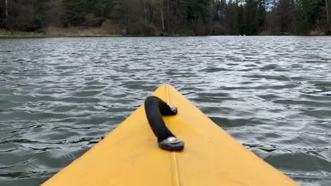 A-Yellow-color-nose-of-kayak-moving-along-in-forest-calm-river-on-a-nice-sunny-day,-outdoor-activities