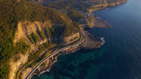 Aerial-View-Of-Sea-Cliff-Bridge-Adjoining-Lawrence-Hargrave-Drive-Bridge-Along-The-Blue-Sea-In-NSW,-Australia