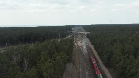 Antenne:-Roter-Und-Grüner-Frachtzug,-Der-Auf-Einer-Eisenbahn-Unter-Einer-Brücke-Fährt