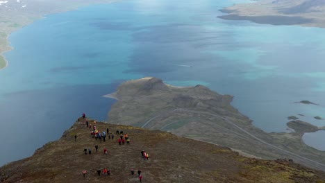 People-standing-near-edge-of-mount-Hólmatindur-with-view-of-Reyðarfjörður-fjord