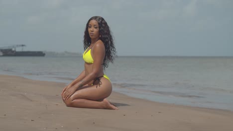 Sexy-bikini-model-kneel-in-the-golden-brown-sand-of-the-Caribbean-island-of-Trinidad-with-a-blurred-background
