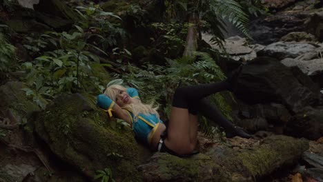 Anime-cosplayer-kicking-her-legs-in-the-air-while-laying-on-the-rocks-at-the-base-of-a-waterfall