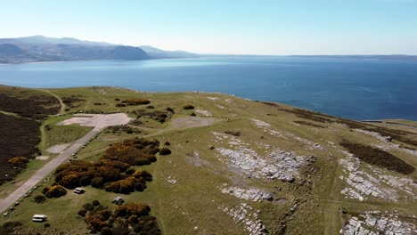 Aerial-view-Great-Orme-landmark-North-Wales-colourful-moorland-mountain-summit-overlooking-Irish-sea-pan-right