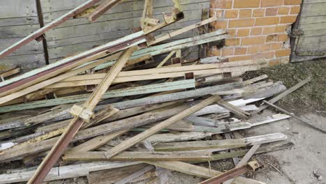 Pile-of-broken-wooden-plank-and-scrap-metal-junk,-pan-right-shot