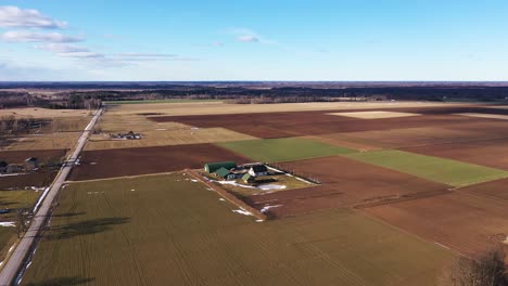 Aerial-dolly-in-over-farmhouse-and-agriculture-land-at-day,-wide-angle