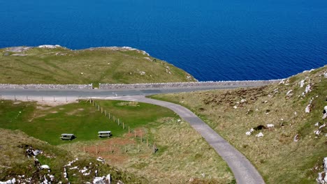Sunny-Great-Orme-mountain-sea-view-North-Wales-aerial-coastal-island-winding-road-moorland-landscape-tilt-up-establishing