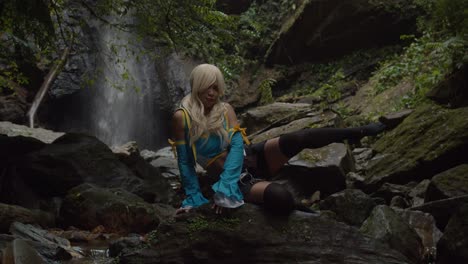 Lucy-heartfilia-cosplayer-sits-on-a-rock-striking-a-pose-at-the-base-of-a-huge-waterfall