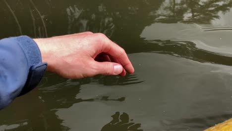 A-man-puts-fingers-down-in-lake-kayaking