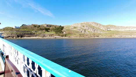 Timelapse-red-fishing-boat-floating-around-colourful-landmark-Great-Orme-North-Wales-island-seascape-viewpoint-from-promenade