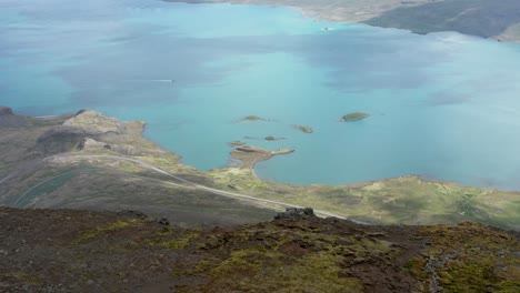 Aerial-past-edge-of-Hólmatindur-mountain-with-blue-fjord-in-Iceland