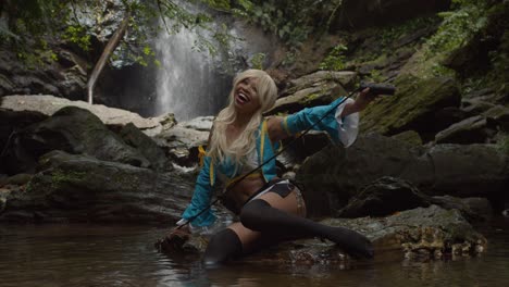 Anime-cosplayer-smile-while-sitting-on-a-rock-at-the-base-of-a-waterfall-and-holding-her-whip
