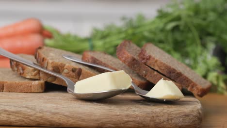 Wooden-cutting-board-with-slices-of-wholemeal-bread-and-two-servings-of-butter