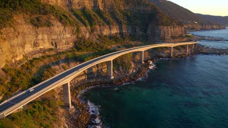 Car-Travelling-At-Sea-Cliff-Bridge-Over-Blue-Sea-In-Sunrise-At-Sydney,-NSW,-Australia