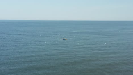 AERIAL:-Blue-Boat-in-the-Sea-on-a-Sunny-Day-with-Fisherman-Catching-Fish