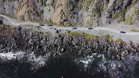 A-birdseye-view-of-a-group-of-off-road-vehicles-driving-on-a-gravel-coastal-road