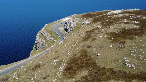 Scenic-Green-Rocky-Moorland-Mountain-Country-Road-Con-Vistas-A-La-Magnífica-Antena-Azul-Del-Mar-Irlandés-Inclinada-Hacia-Abajo