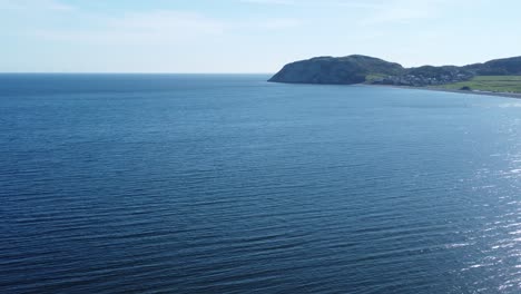 Shimmering-blue-Irish-sea-Llandudno-North-Wales-coastline-aerial-promenade-resort-panning-right