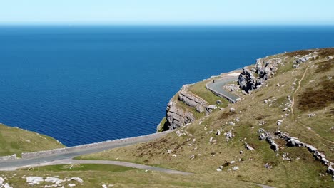 Szenische-Grüne-Wanderer-Wahrzeichen-Berg-Landstraße-Mit-Blick-Auf-Wunderschöne-Blaue-Irish-Sea-Luftbild-Dolly-Links