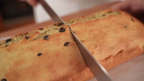 Cutting-Chocolate-Chip-Bread-in-Half-with-Knife,-Close-Up-in-Slow-Motion