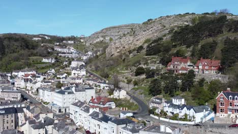 Colourful-Llandudno-seaside-holiday-town-hotels-against-Great-Orme-mountain-aerial-view-slow-right-panning-shot