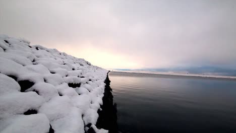 calming-shot-of-a-snow-covered-damm-close-up-at-water-level-,-gaddins-dam-todmorden