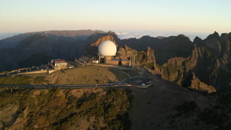Drone-aerial-footage-flying-over-Pico-do-Arieiro,-and-the-radar-station-on-the-peaks-at-sunrise-with-surrunding-mountains-of-Maderia