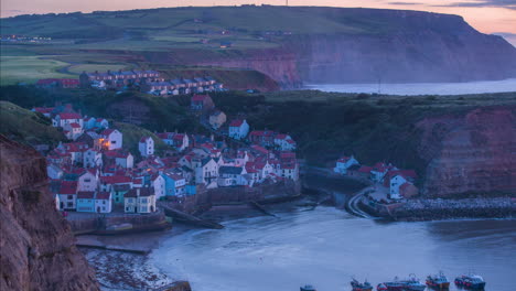 Staithes-Harbour-and-Village-Timelapse-from-headland-with-mist-through-to-dusk-with-village-lights-illuminating,-atmospheric