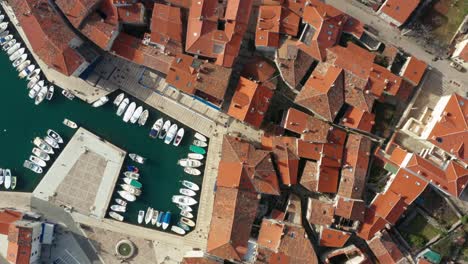 Aerial-shot-descending-toward-a-marina-on-the-island-of-Cres,-Croatia-on-a-bright-day