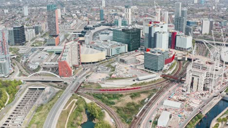 Pan-down-dolly-forward-drone-shot-of-dlr-and-London-overground-train-in-Stratford-city