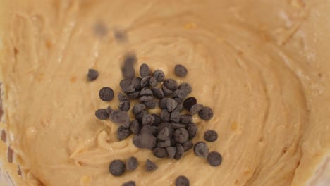 Chocolate-Chips-Fall-in-Sweet-Bread-Dough,-Top-View-in-Slow-Motion